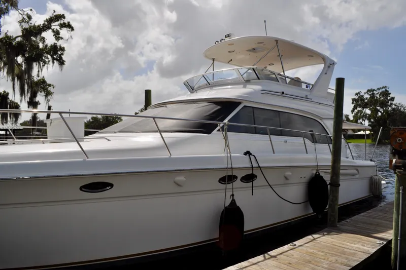 King Leisure Yacht Photos Pics 2002 Sea Ray 480 Sedan Bridge yacht docked by a wooden pier under cloudy skies.