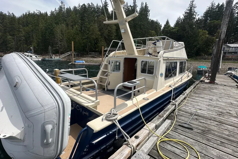 Blue Heron Yacht Photos Pics 2003 Coastal Craft 320 Cruiser docked by a forested shoreline.