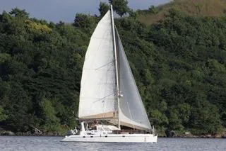 Casuarina Yacht Photos Pics Sailing yacht Voyage Yachts Norseman 430, 2000 model, cruising near lush green shoreline.