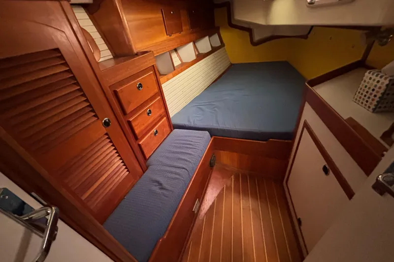 Custom Yacht Photos Pics Cozy cabin interior of 2000 Sabre 452 sailboat with wooden furnishings and blue cushions.