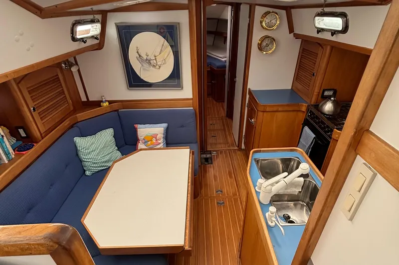 Custom Yacht Photos Pics Interior of 2000 Sabre 452 sailboat with blue seating, wooden accents, and compact kitchen area.