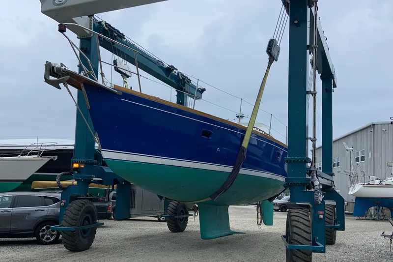 Custom Yacht Photos Pics Blue Sabre 452 sailboat from 2000 being lifted by a boat hoist in a marina.