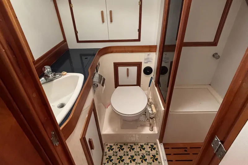 Custom Yacht Photos Pics Compact boat bathroom with sink, toilet, and shower in a 2000 Sabre 452 model.