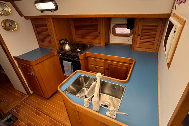 Custom Yacht Photos Pics 2000 Sabre 452 yacht kitchen with blue countertops, wooden cabinets, and stainless steel sink.