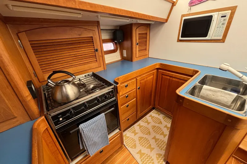 Custom Yacht Photos Pics Compact kitchen in a 2000 Sabre 452 yacht with stove, sink, and microwave.