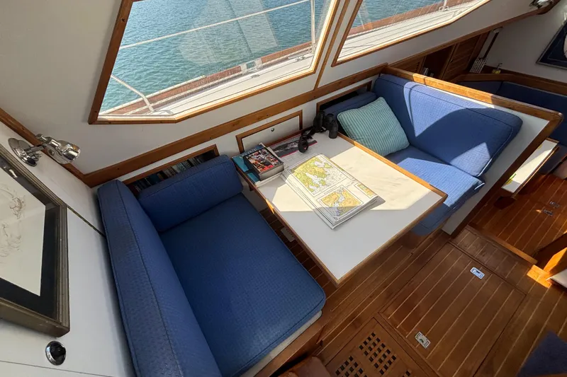 Custom Yacht Photos Pics Cozy Sabre 452 yacht interior with blue seating, nautical chart, and ocean view through windows.