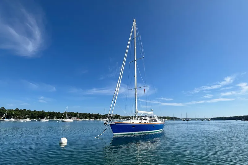 Custom Yacht Photos Pics Sailboat Sabre 452 (2000) anchored in a serene harbor under a clear blue sky.