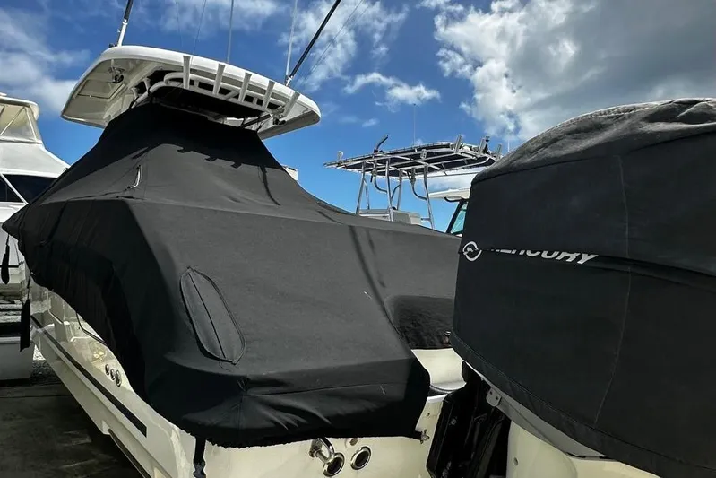  Yacht Photos Pics 2017 Boston Whaler 330 Outrage boat covered, docked under a partly cloudy sky.