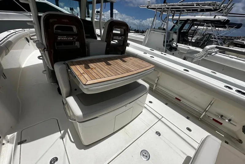  Yacht Photos Pics 2017 Boston Whaler 330 Outrage boat interior with seating and wooden table.