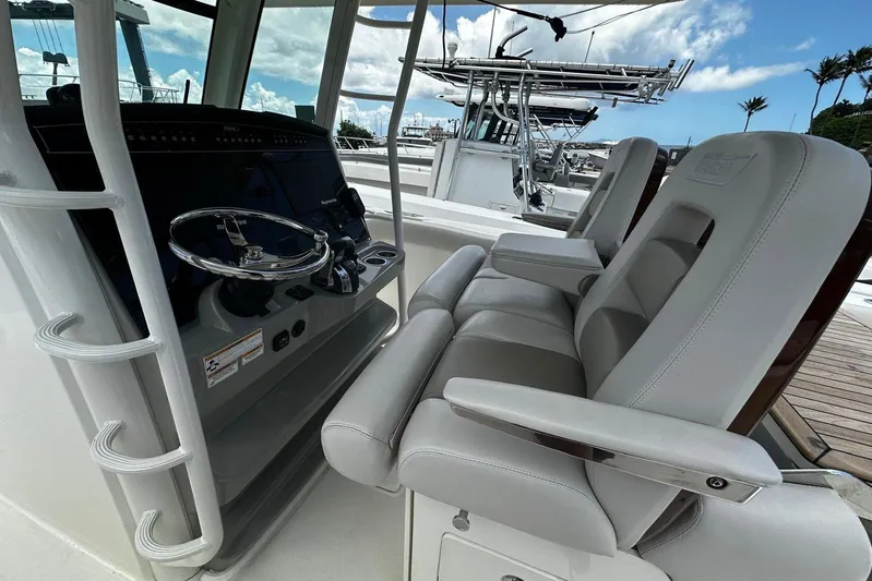  Yacht Photos Pics 2017 Boston Whaler 330 Outrage helm with dual seats and steering wheel, docked under blue sky.
