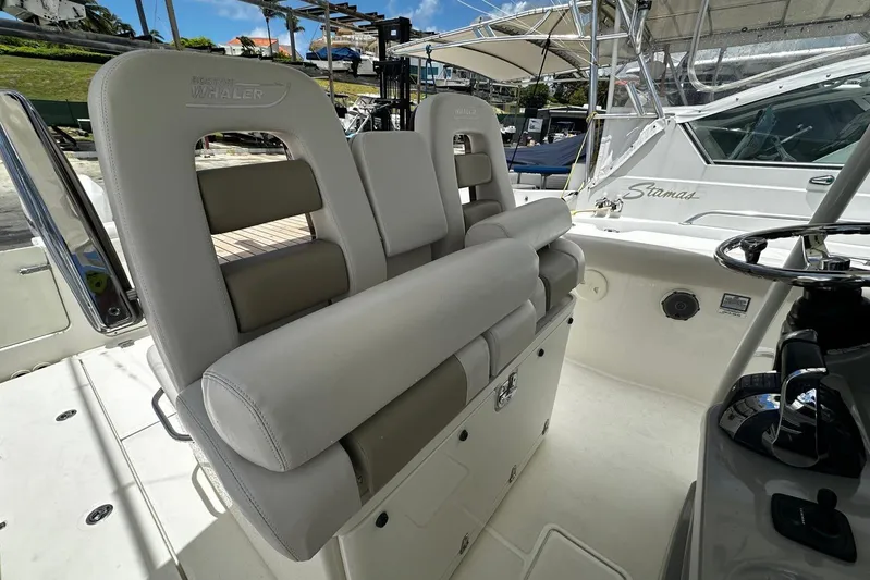  Yacht Photos Pics 2017 Boston Whaler 330 Outrage boat interior with cushioned seating and steering wheel.