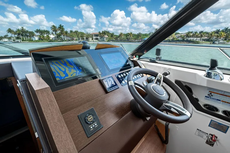 Southwind Yacht Photos Pics 2018 Tiara Yachts C44 Coupe helm with navigation screens and steering wheel, overlooking scenic waterway.