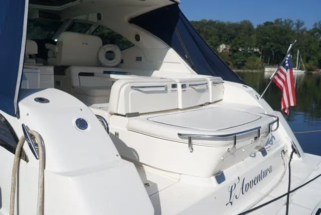 L' Aventura Yacht Photos Pics 2010 Sea Ray 470 Sundancer yacht with American flag, docked on a serene lake.