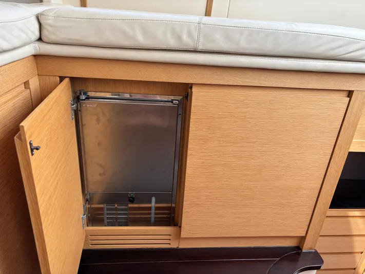  Yacht Photos Pics Wooden cabinet with open door revealing a compact fridge inside a 2011 Pershing 64 yacht.