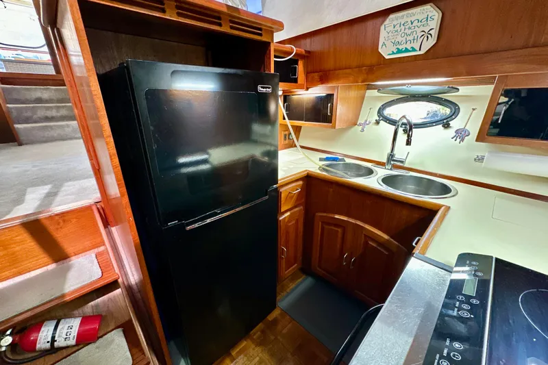 Anchored Souls Yacht Photos Pics 1988 Californian 45 Motor Yacht kitchen with black fridge, dual sinks, and wooden cabinetry.