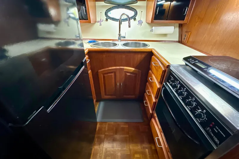 Anchored Souls Yacht Photos Pics 1988 Californian 45 Motor Yacht kitchen with stove, sink, and wooden cabinetry.