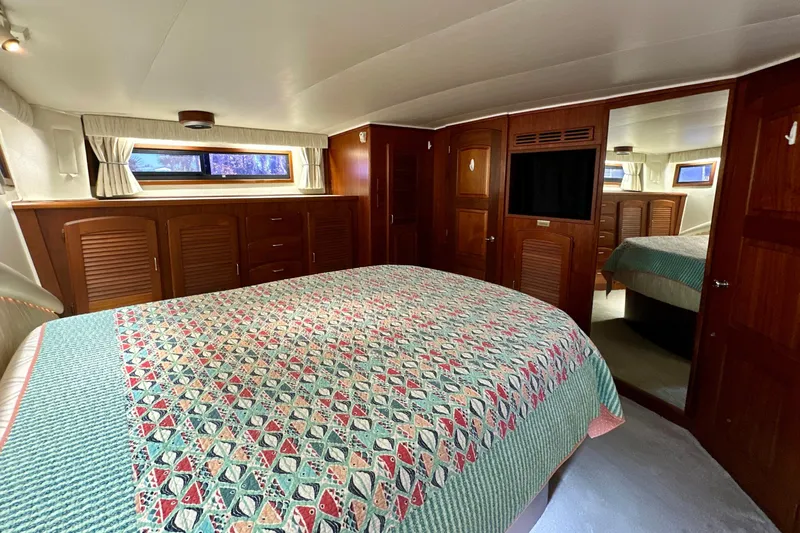 Anchored Souls Yacht Photos Pics Luxurious bedroom interior of 1988 Californian 45 Motor Yacht with patterned bedding and wooden cabinetry.