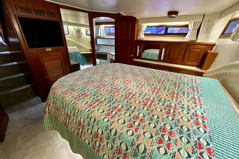 Anchored Souls Yacht Photos Pics 1988 Californian 45 Motor Yacht interior with patterned bedspread and wooden cabinetry.