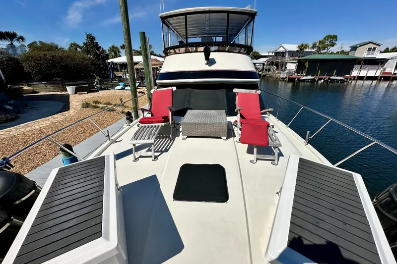 Anchored Souls Yacht Photos Pics 1988 Californian 45 Motor Yacht with deck chairs, docked in a serene marina setting.