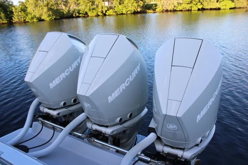  Yacht Photos Pics Triple Mercury outboard engines on a 2019 Conch 33 boat, set against a serene water backdrop.
