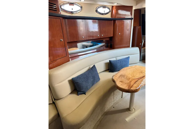  Yacht Photos Pics 2006 Sea Ray 340 Sundancer interior with curved seating, wooden table, and blue cushions.
