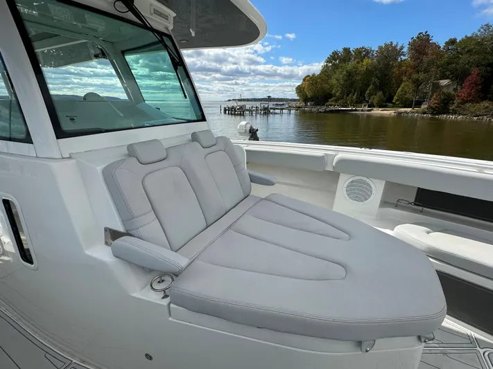  Yacht Photos Pics 2019 HCB Siesta boat with cushioned seating, docked by a scenic waterfront.