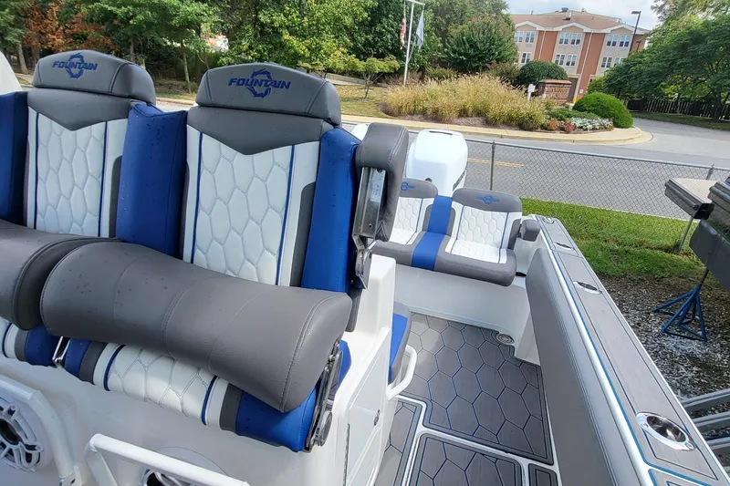  Yacht Photos Pics 2022 Fountain 34 SC boat interior with blue and white seating, parked outdoors.