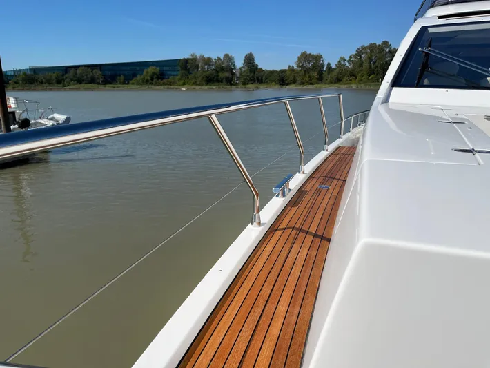  Yacht Photos Pics Azimut 77S 2016 yacht deck with wooden flooring and railing, on a calm river.