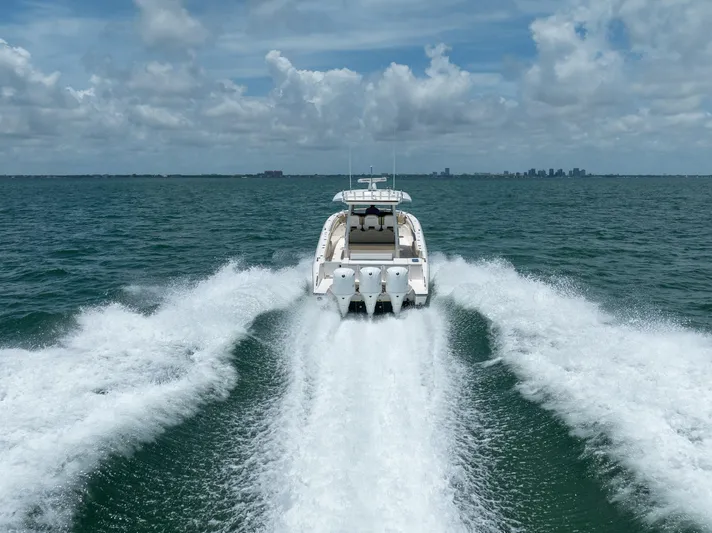 100 Percent Yacht Photos Pics 2018 Pursuit S 368 Sport boat cruising on open water with city skyline in background.