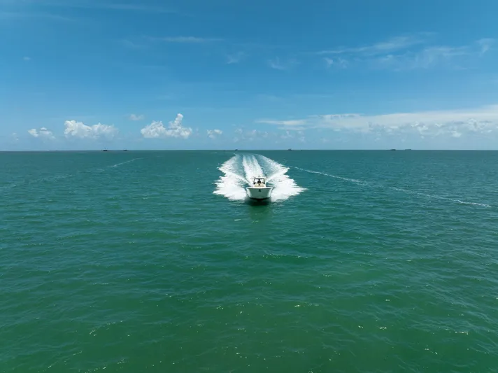 100 Percent Yacht Photos Pics 2018 Pursuit S 368 Sport boat cruising on open ocean under clear blue sky.