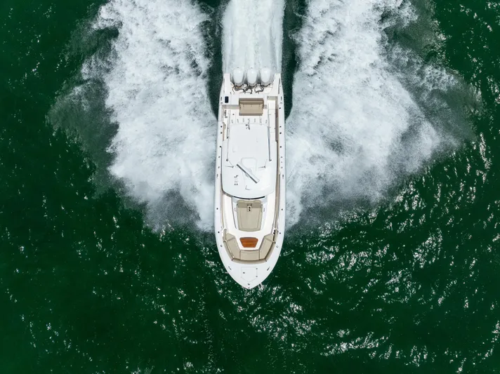 100 Percent Yacht Photos Pics 2018 Pursuit S 368 Sport boat cruising on open water, aerial view.