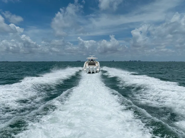 100 Percent Yacht Photos Pics 2018 Pursuit S 368 Sport boat cruising on open ocean under cloudy sky.