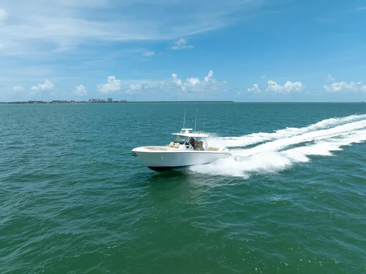 100 Percent Yacht Photos Pics 2018 Pursuit S 368 Sport boat cruising on open sea under clear blue sky.