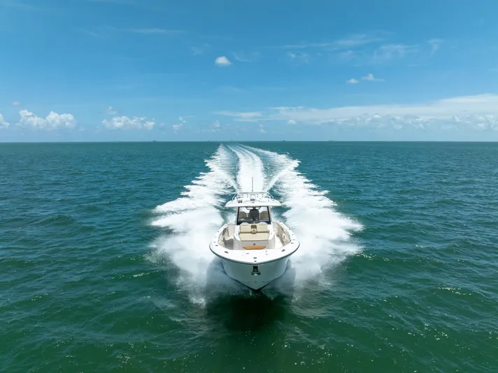 100 Percent Yacht Photos Pics 2018 Pursuit S 368 Sport boat cruising on open ocean under clear blue sky.