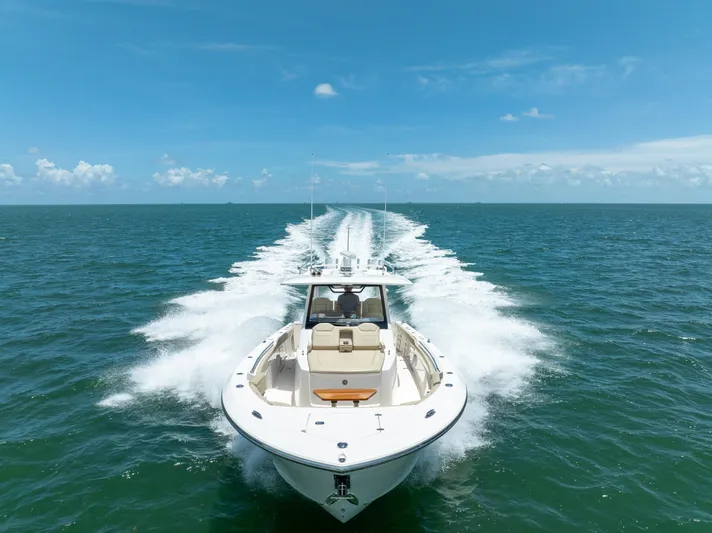 100 Percent Yacht Photos Pics 2018 Pursuit S 368 Sport boat cruising on open ocean under clear blue sky.
