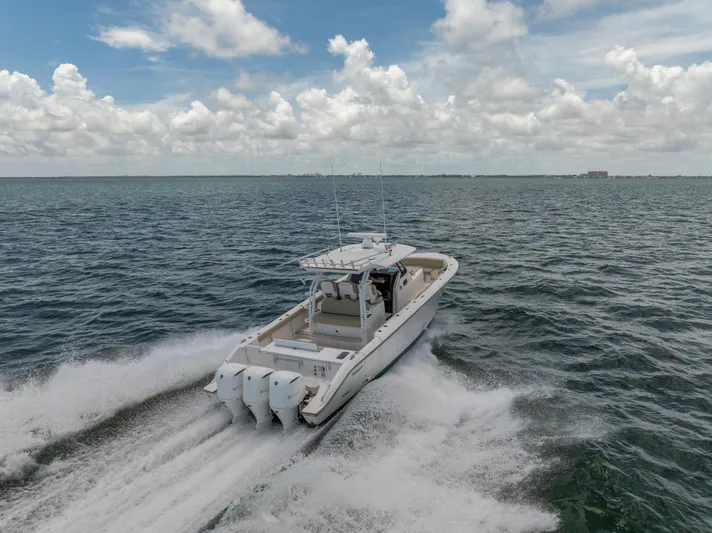 100 Percent Yacht Photos Pics 2018 Pursuit S 368 Sport boat cruising on open water under a cloudy sky.