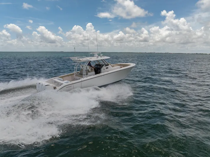 100 Percent Yacht Photos Pics 2018 Pursuit S 368 Sport boat cruising on open water under a cloudy sky.