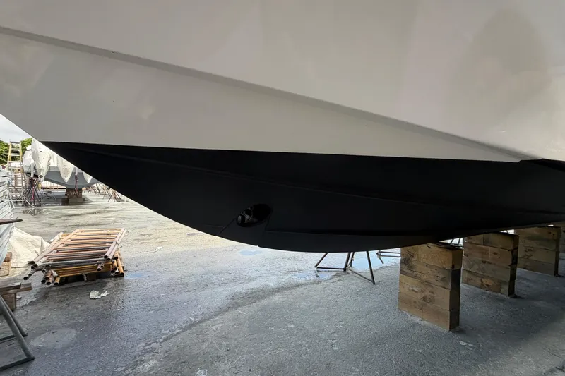 100 Percent Yacht Photos Pics 2018 Pursuit S 368 Sport boat hull on dry dock, supported by wooden blocks.