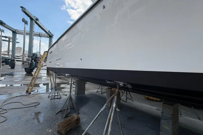100 Percent Yacht Photos Pics 2018 Pursuit S 368 Sport boat on stands in a marina, under maintenance.