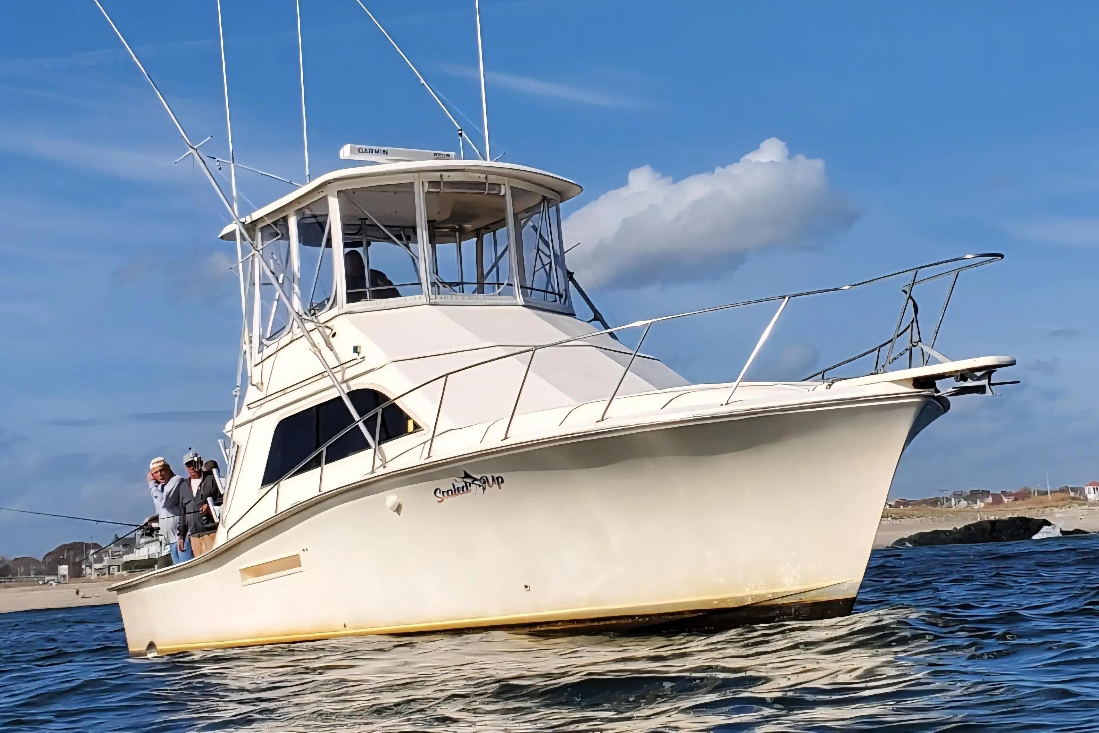 1991 Pacemaker 37 Sportfisherman boat on water, with people fishing, under clear blue sky.