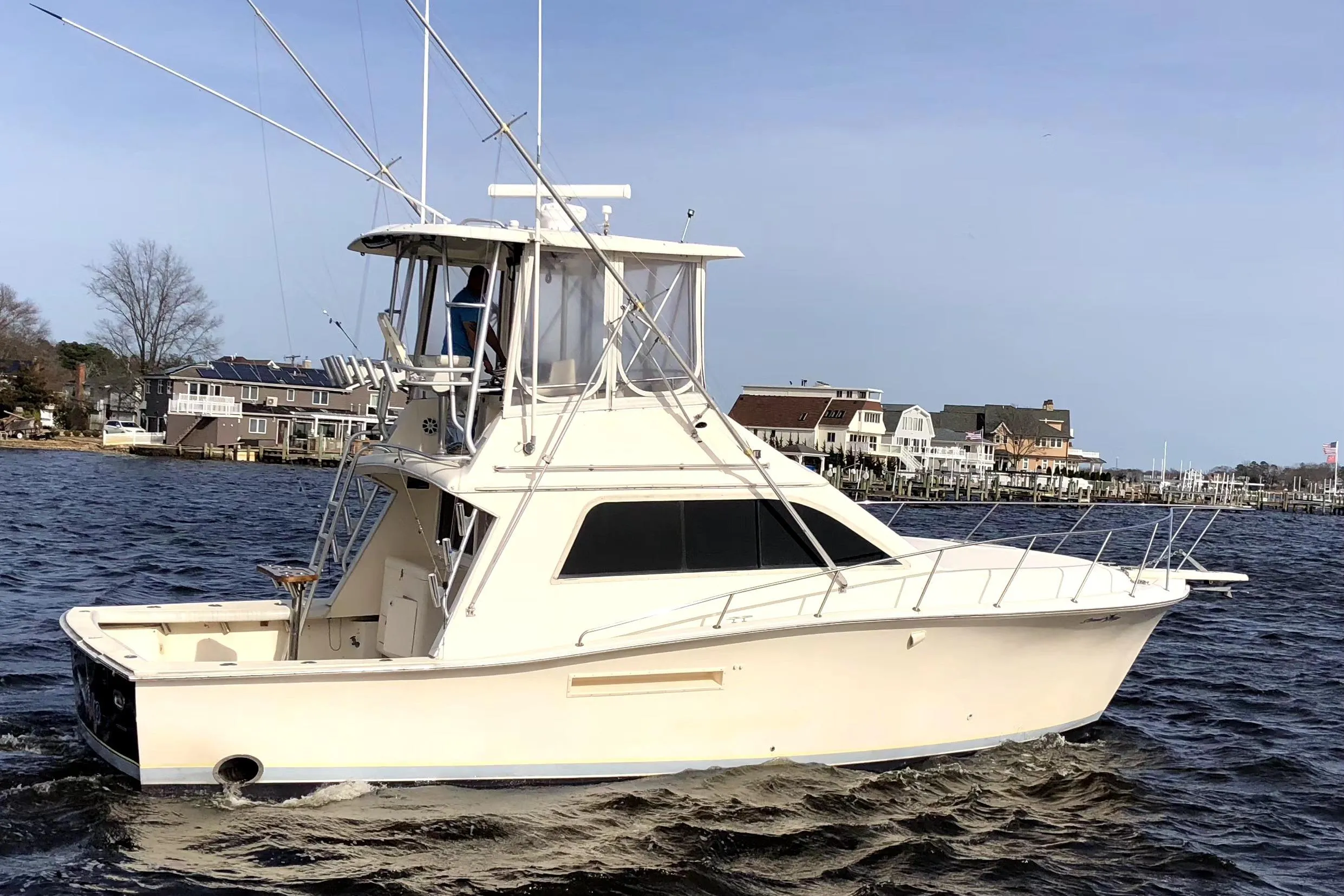 1991 Pacemaker 37 Sportfisherman boat on water near residential shoreline.