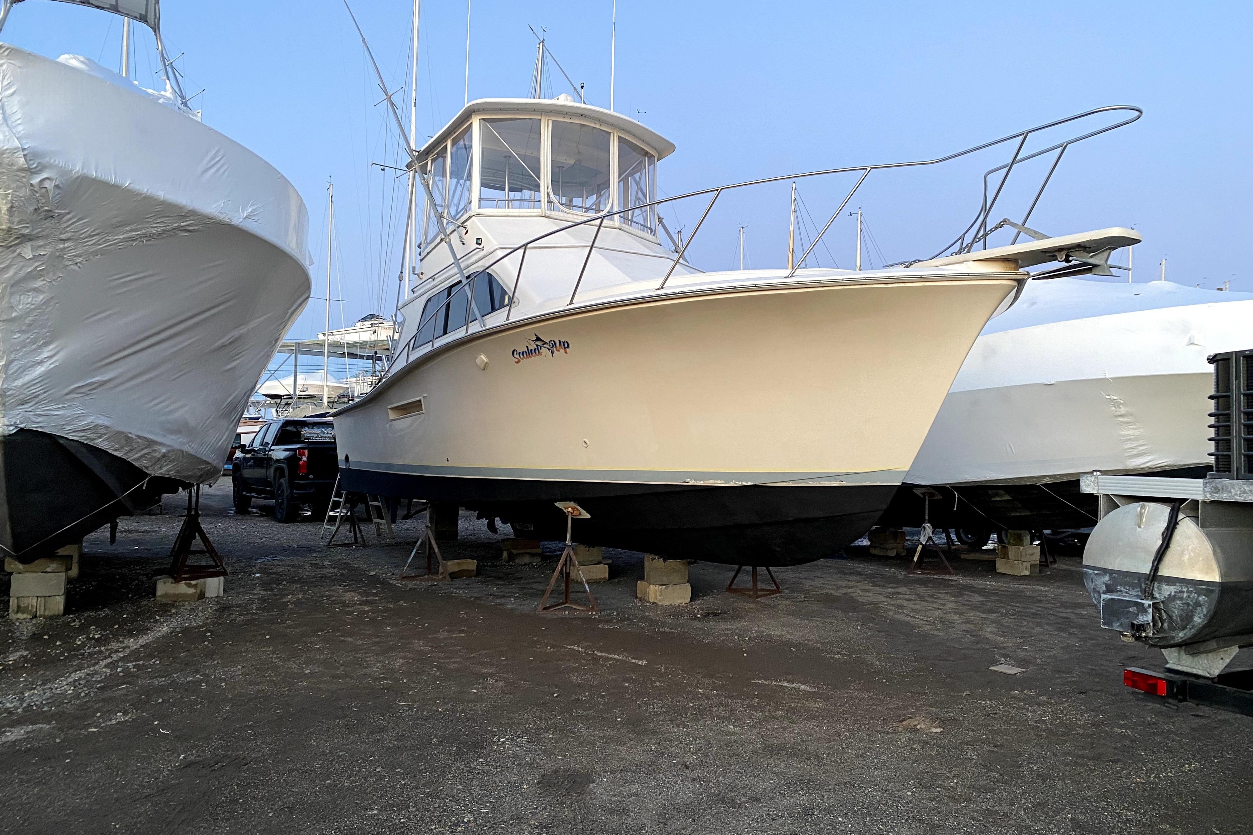 1991 Pacemaker 37 Sportfisherman boat on stands in a marina, surrounded by other vessels.