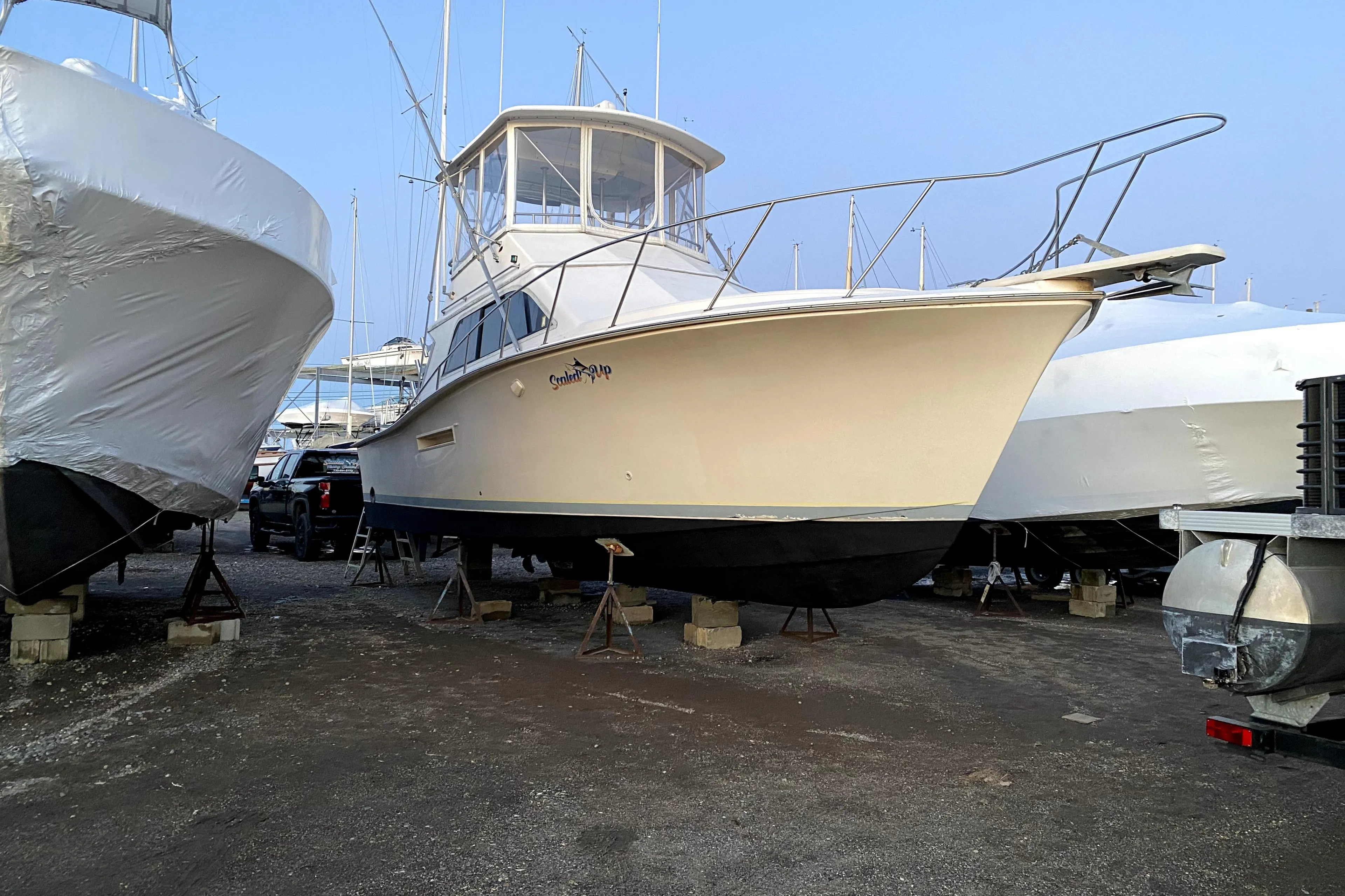 1991 Pacemaker 37 Sportfisherman boat on stands in a marina, surrounded by other vessels.