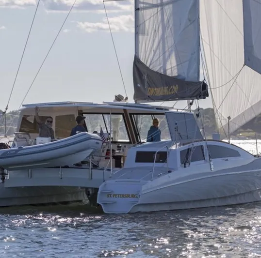 Surfer Girl Yacht Photos Pics 2018 Maine Cat 38 LS sailing on water with people onboard, featuring a dinghy and sails.