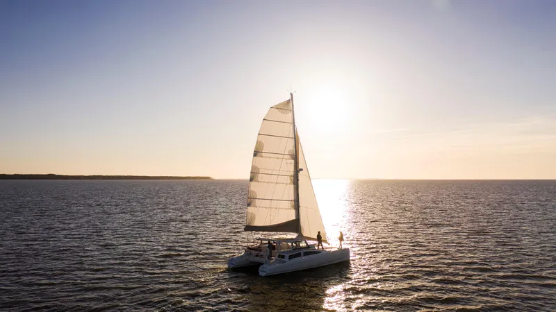 Surfer Girl Yacht Photos Pics Sailing catamaran Maine Cat 38 LS, 2018, on open water at sunset.