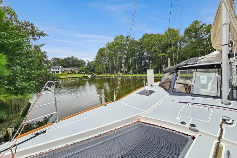 Surfer Girl Yacht Photos Pics 2018 Maine Cat 38 LS catamaran docked by a serene, tree-lined waterfront.