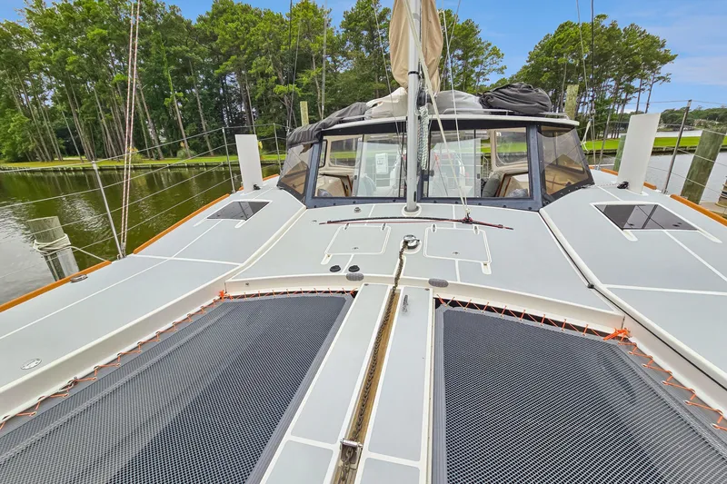 Surfer Girl Yacht Photos Pics 2018 Maine Cat 38 LS catamaran deck with netting, docked near lush trees.