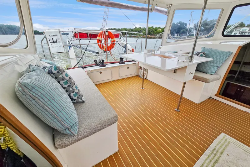 Surfer Girl Yacht Photos Pics 2018 Maine Cat 38 LS interior with cushioned seating and table, overlooking water.