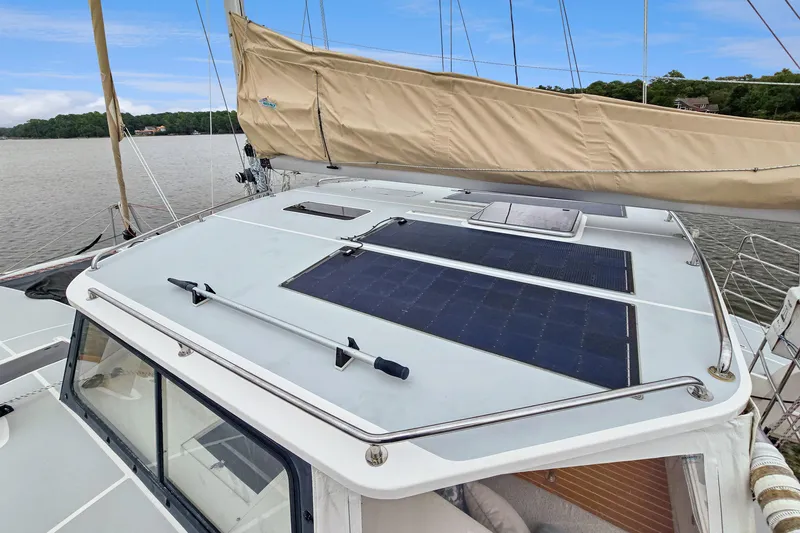 Surfer Girl Yacht Photos Pics 2018 Maine Cat 38 LS sailboat with solar panels on deck, docked by a scenic shoreline.
