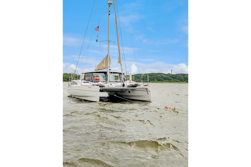 Surfer Girl Yacht Photos Pics 2018 Maine Cat 38 LS catamaran sailing on a calm river under a clear blue sky.